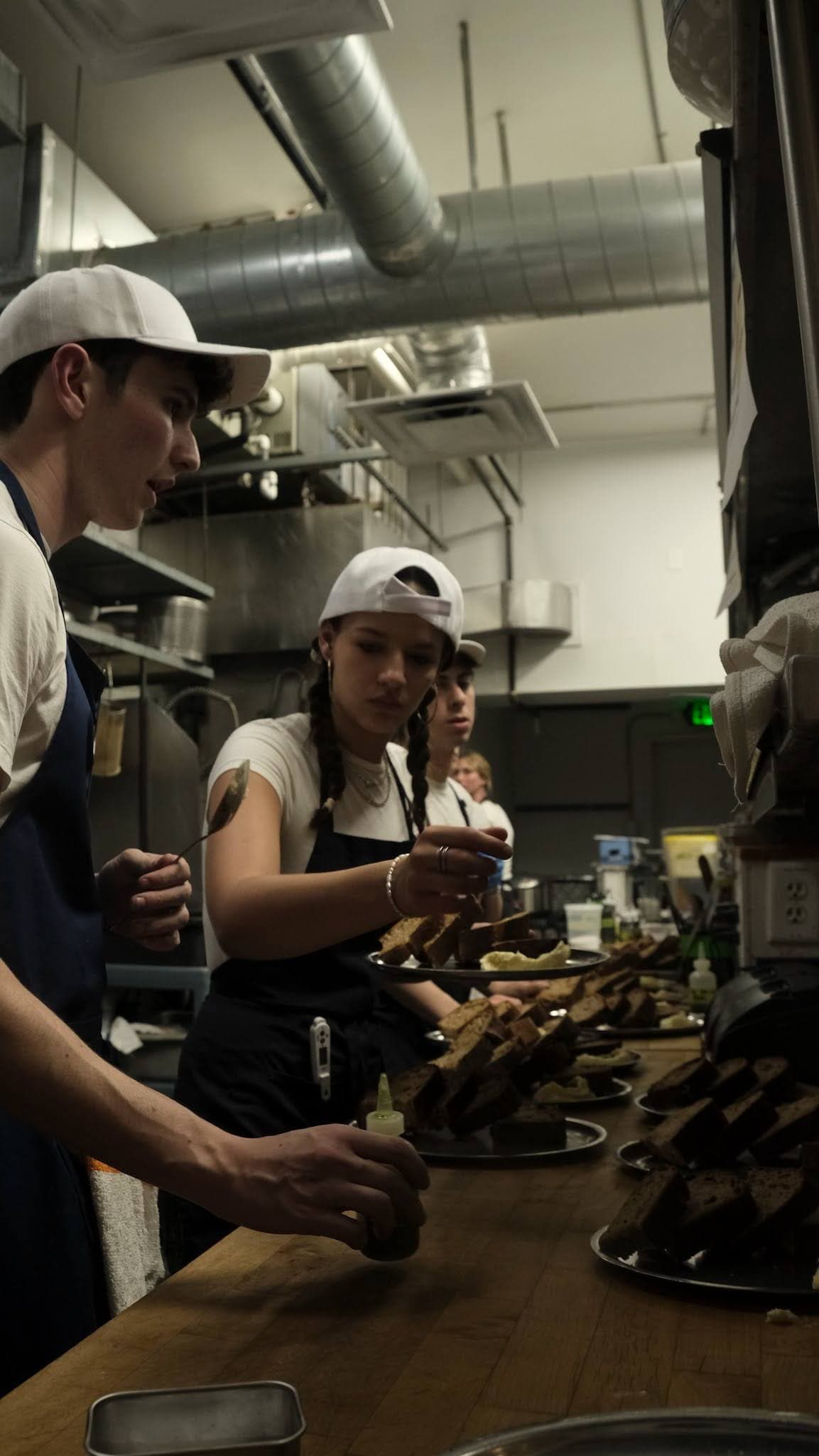 Julia plating dishes on the line in a restaurant kitchen alongside fellow cooks