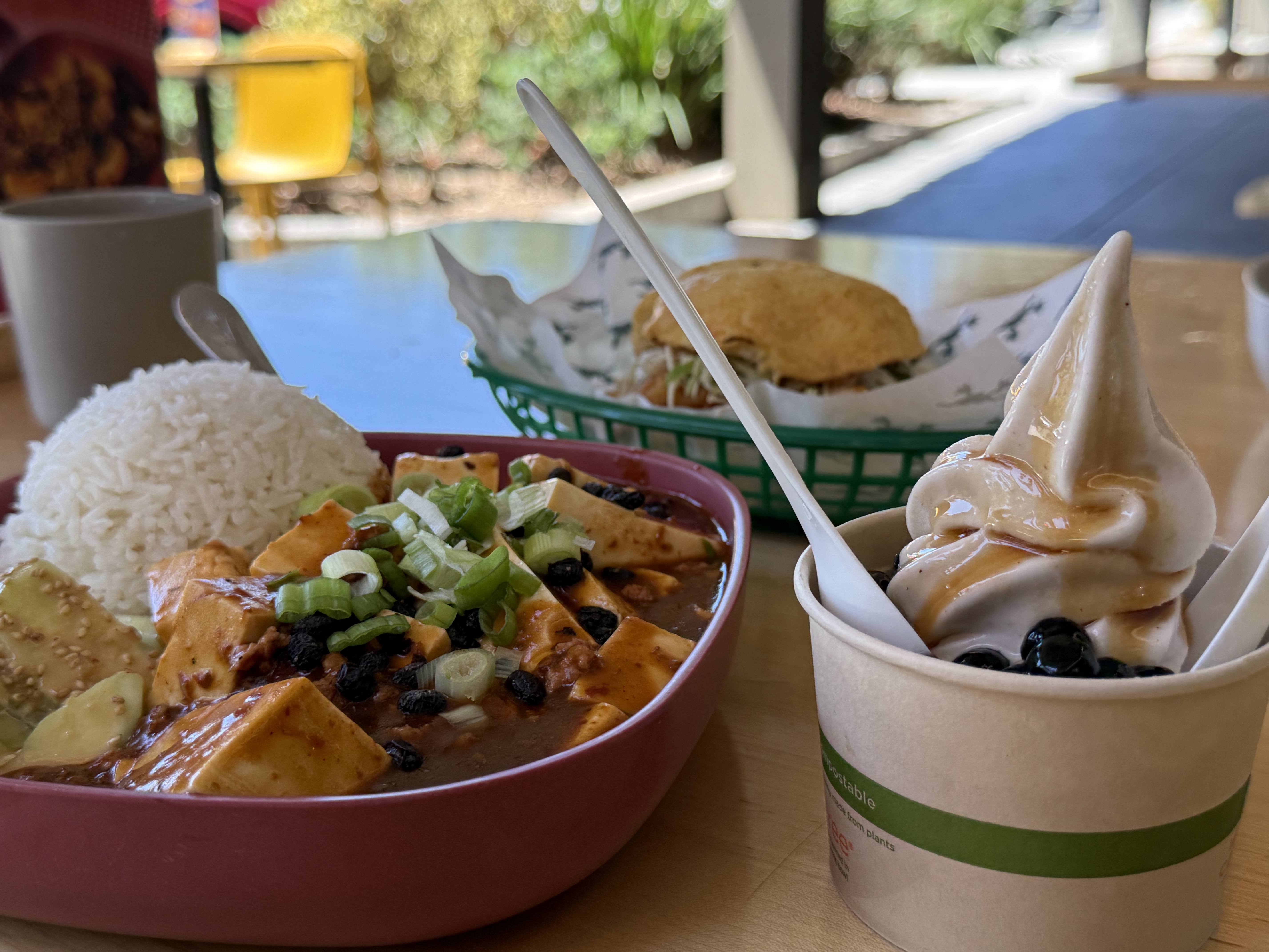 A lunch spread at Mamahuhu — a bowl of mapo tofu over rice, a sandwich, and a cup of soft-serve topped with boba